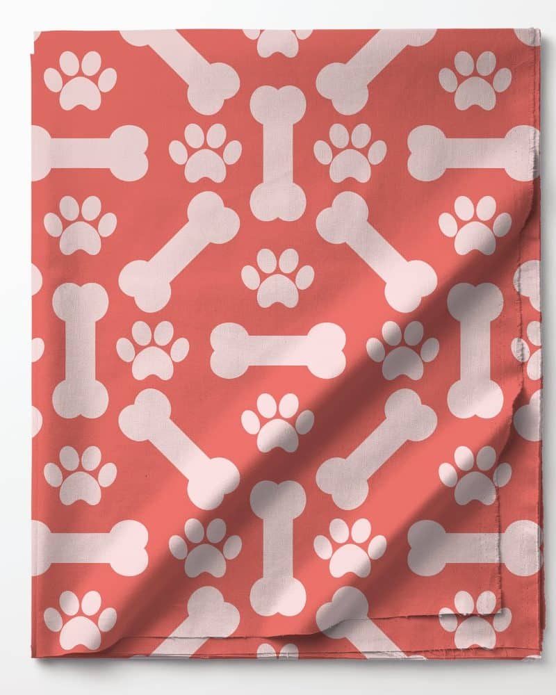 Coral fabric with a repeating pattern of white bones and paw prints.