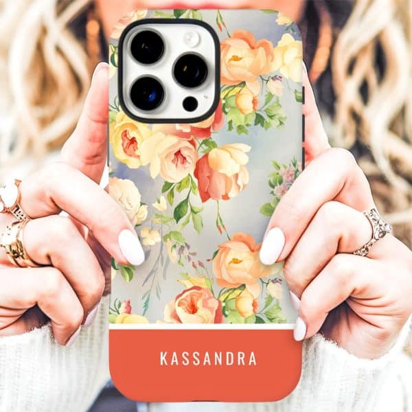 A Woman'S Hands Holding A Phone Case With A Floral Design And The Name Kassandra On A Coral Band.