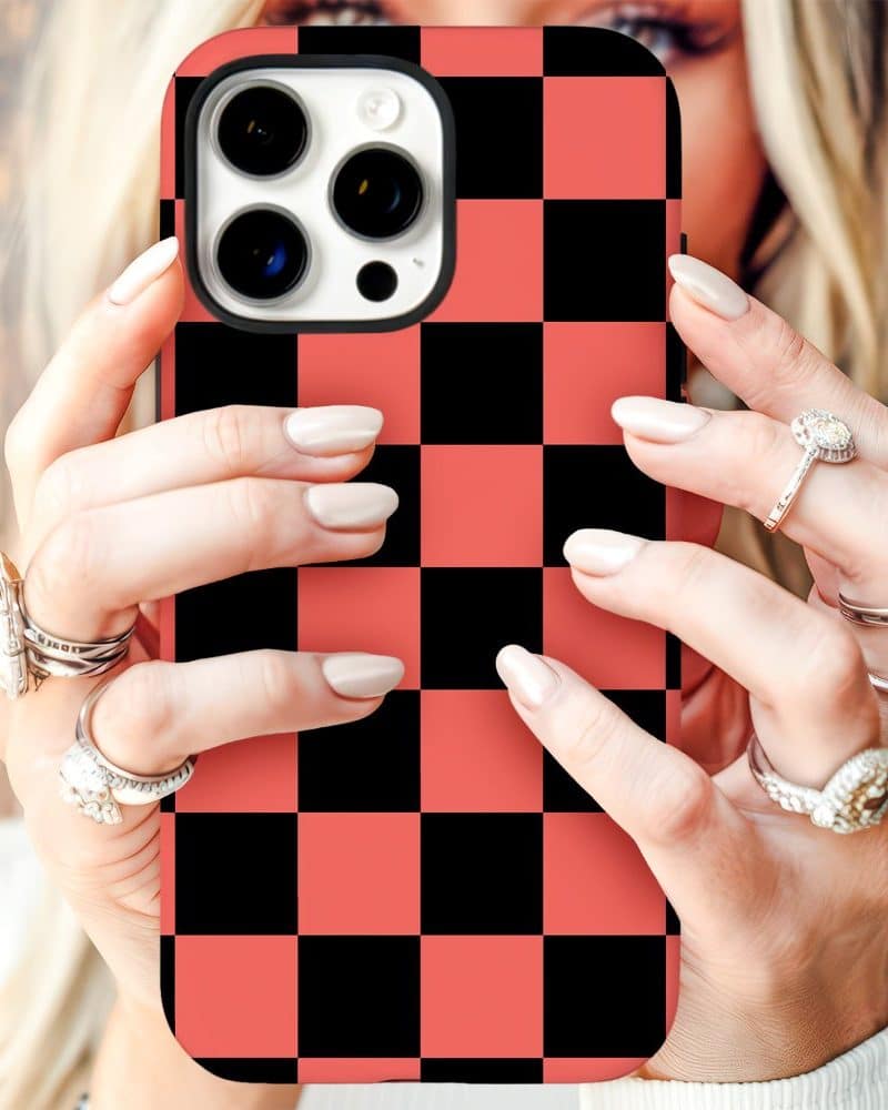 Woman's hands holding a coral and black checkered phone case.