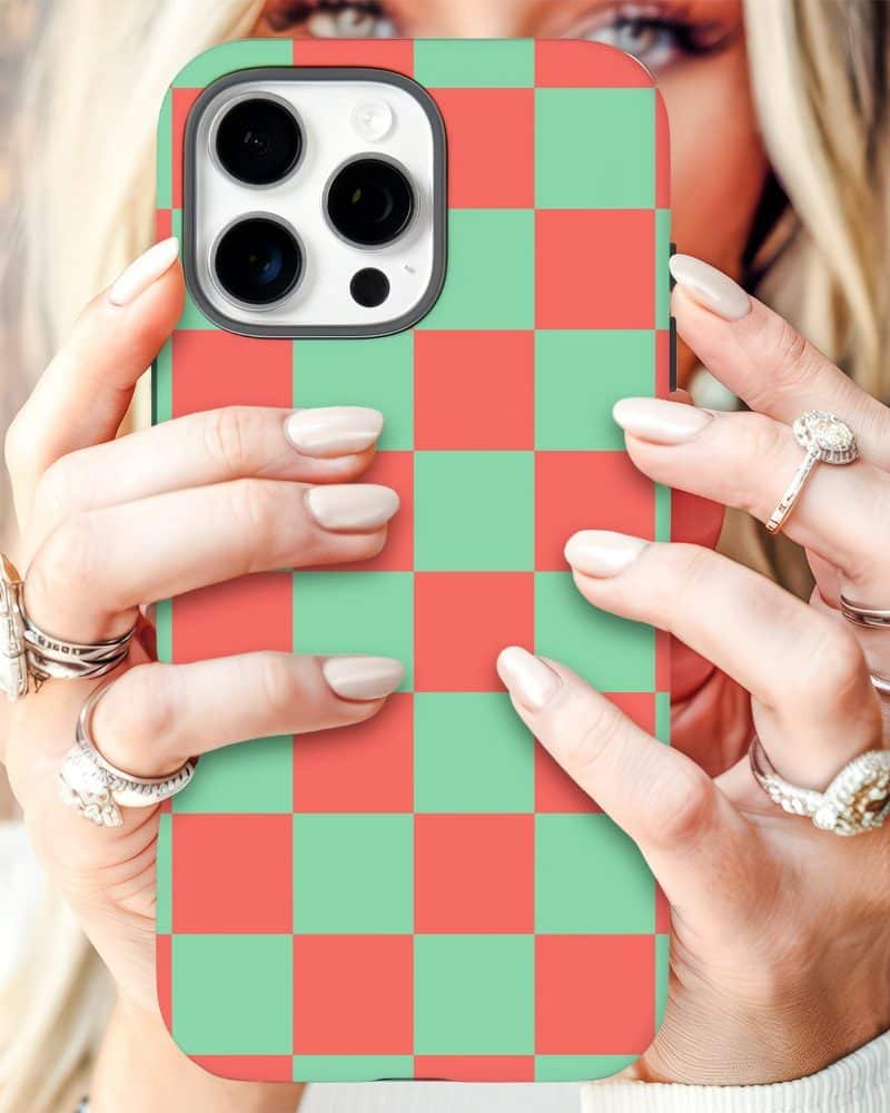 Close-up of hands holding a phone with a red and green checkered phone case.