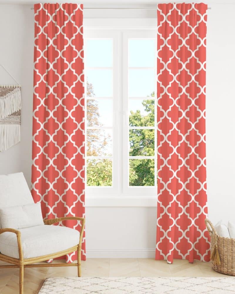 Coral-colored curtains with a white quatrefoil pattern hang in a window.