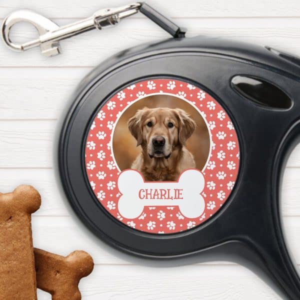 Black Retractable Dog Leash With A Coral-Colored Circle Featuring A Golden Retriever Portrait, Paw Prints, And The Name Charlie.