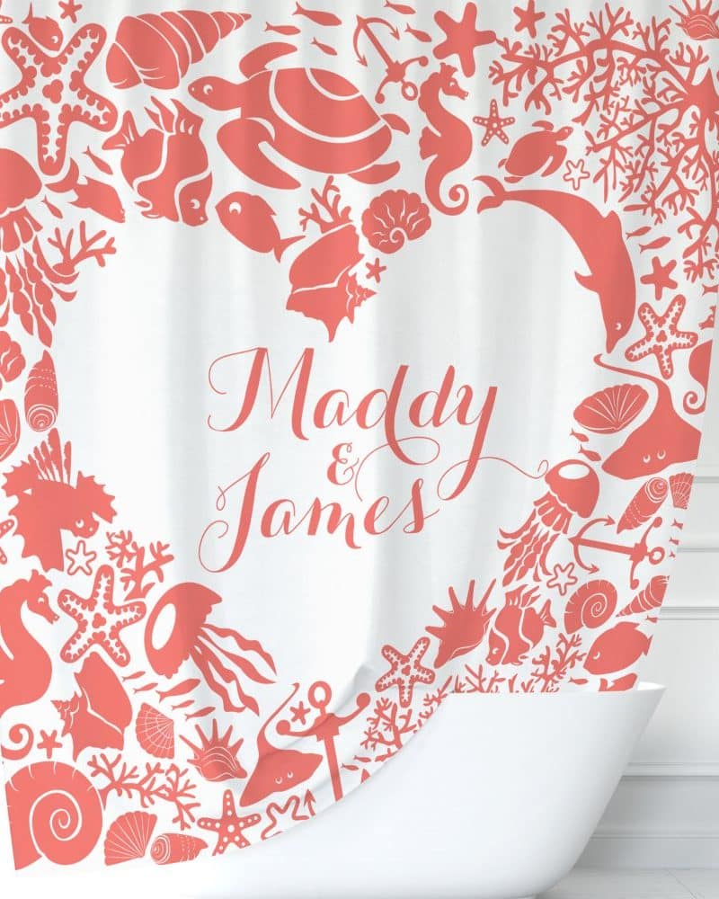 Coral-colored sea life designs form a heart shape around the names Maddy and James on a white shower curtain.