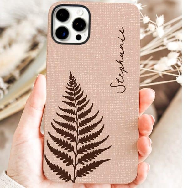 A Hand Holds A Blush-Pink Phone Case Featuring A Dark Brown Fern And The Name Stephanie.