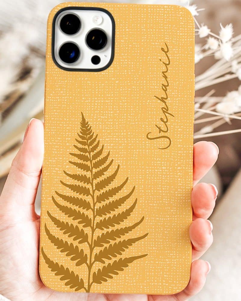 A mustard yellow phone case with a gold fern design and the name Stephanie.