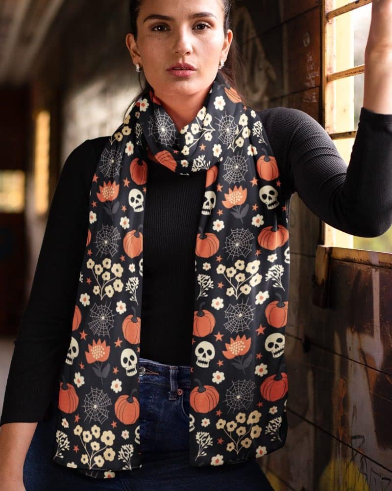 Woman wearing a black Halloween-themed scarf with pumpkins and skulls.