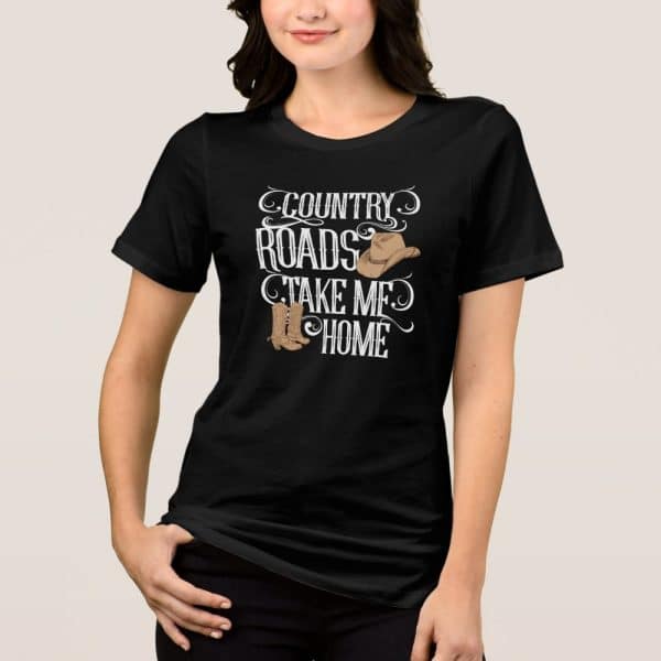 Woman Wearing A Black T-Shirt With A Country Design Featuring A Cowboy Hat And Boots, And The Text Country Roads Take Me Home.