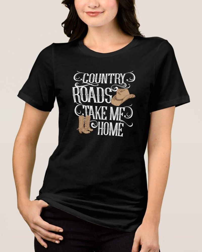 Woman wearing a black t-shirt with a country design featuring a cowboy hat and boots, and the text Country Roads Take Me Home.