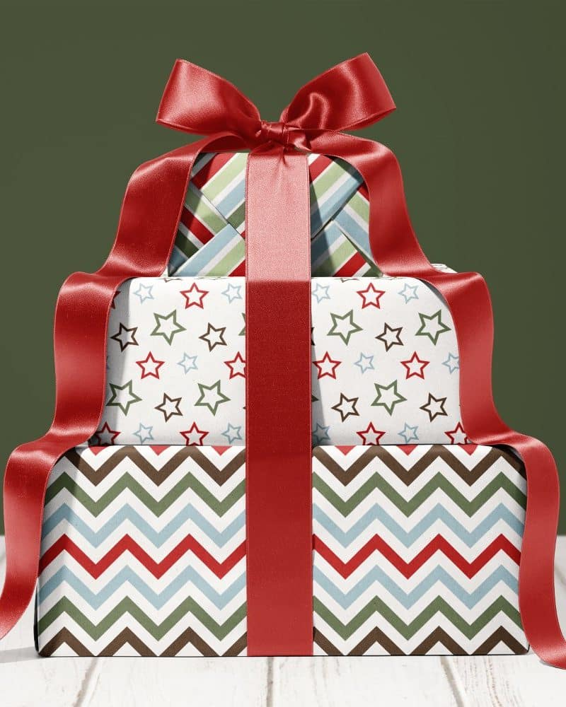 Stack of three festively wrapped presents with a large red ribbon.