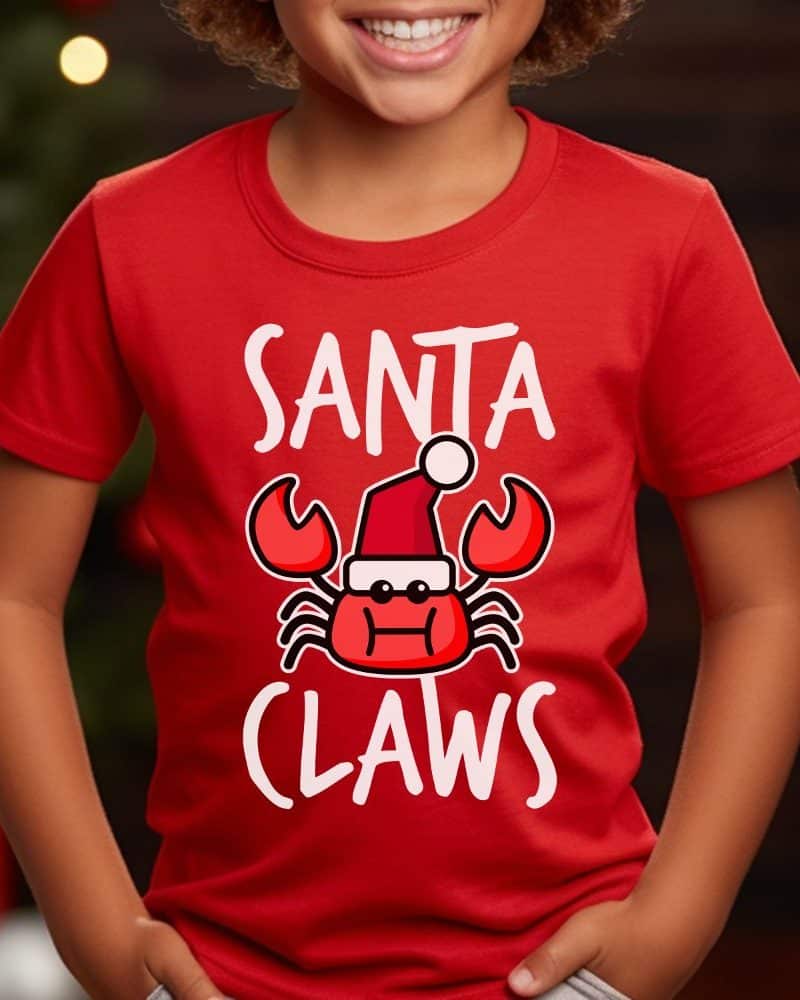 Child wearing a red t-shirt with a design that says Santa Claws and features a cartoon crab wearing a Santa hat.
