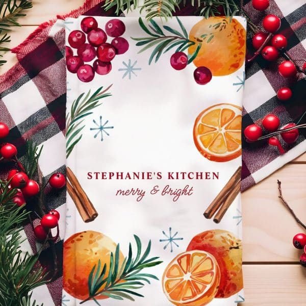 Christmas Kitchen Tea Towel With Oranges, Cranberries, Rosemary, And Cinnamon Sticks. The Text &Quot;Stephanie'S Kitchen Merry &Amp; Bright&Quot; Is Also On The Towel.