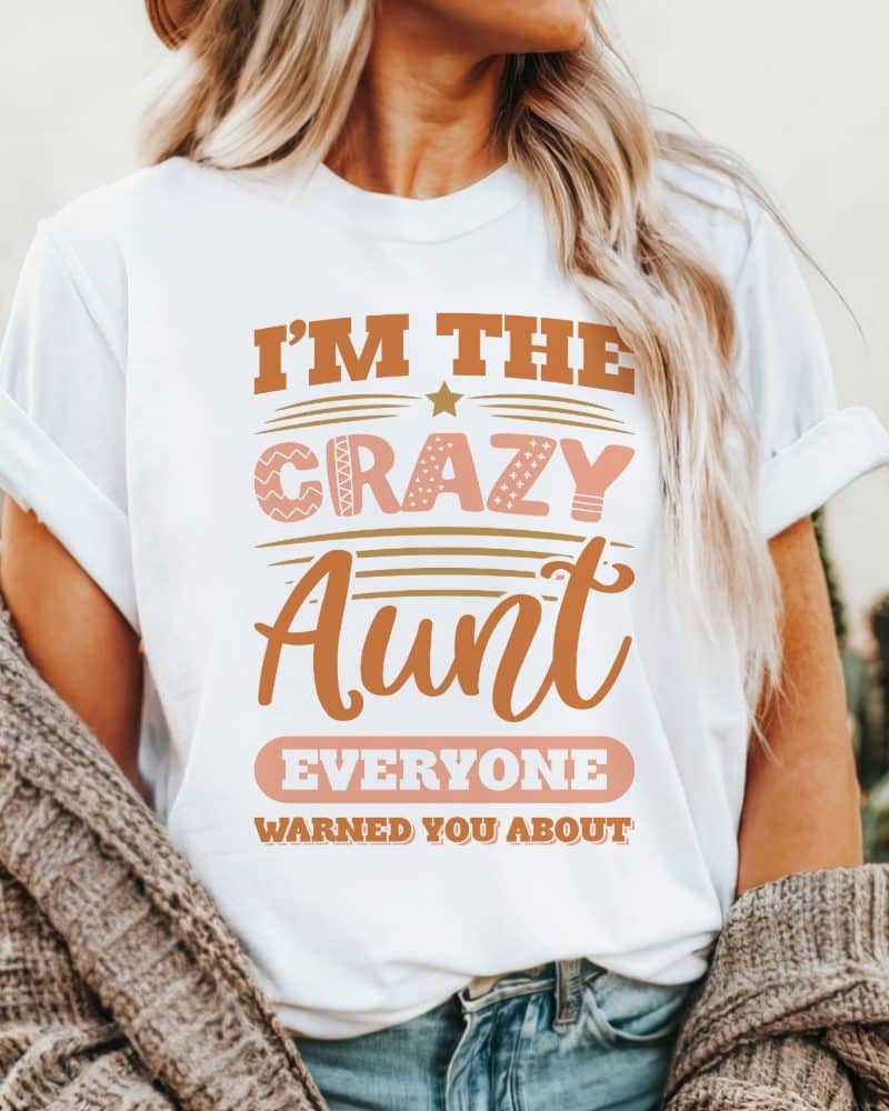 White t-shirt with the text Im the crazy aunt everyone warned you about in peach and gold lettering.