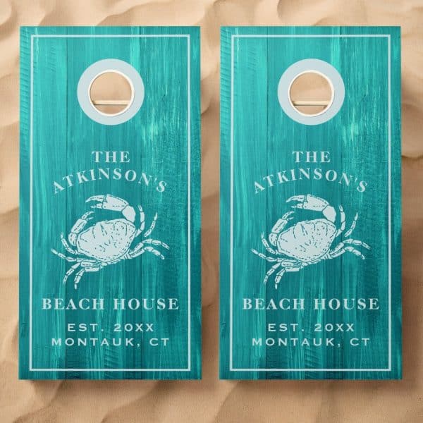 Two Teal Cornhole Boards With A Crab Design, The Atkinson'S Beach House Name, And Establishment Year.