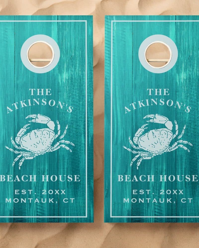 Two teal cornhole boards with a crab design, the Atkinson's Beach House name, and establishment year.