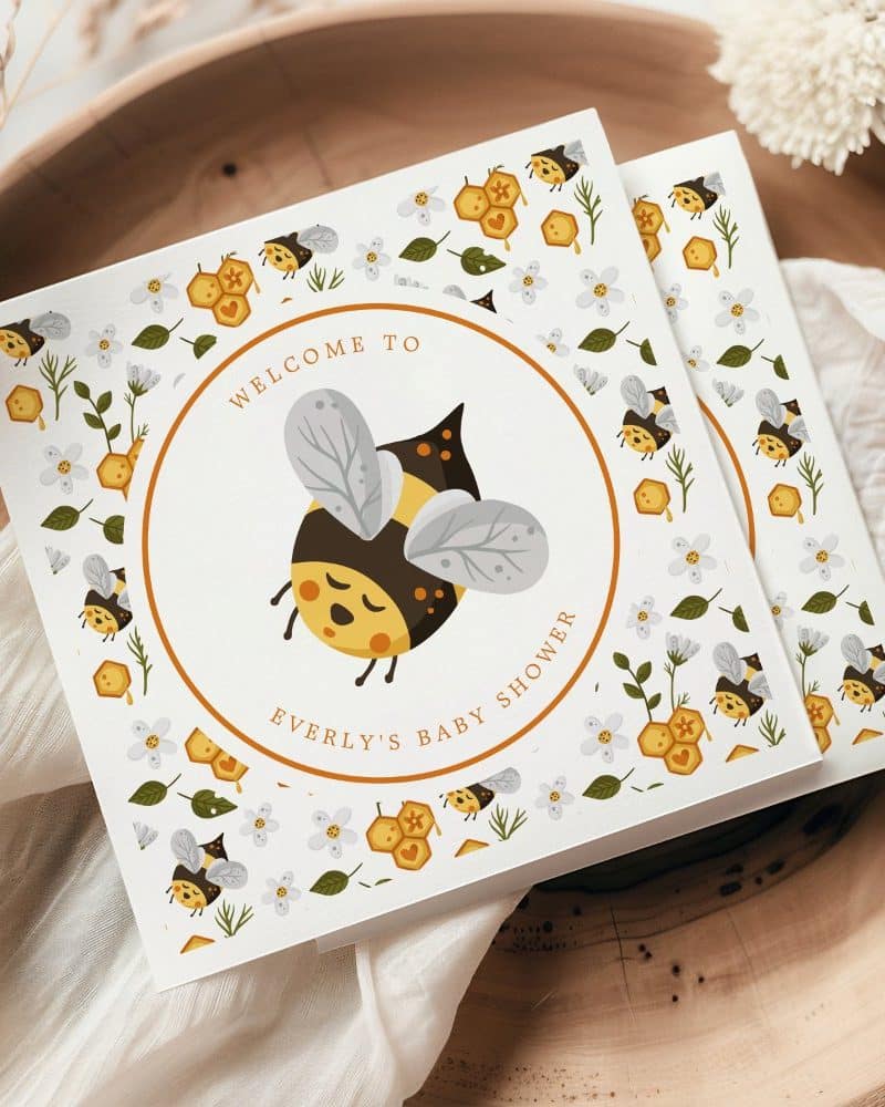 Baby shower invitation featuring a cartoon bumblebee and honeycomb pattern.