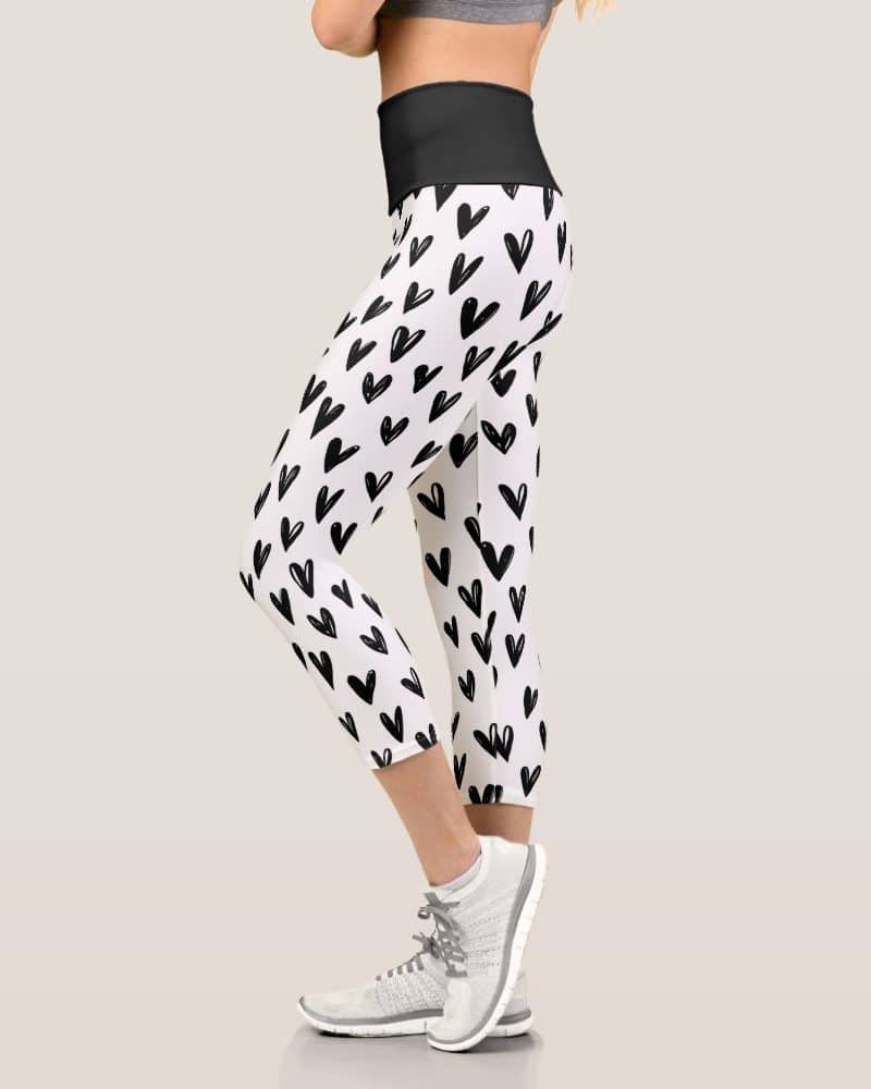 Woman's cropped leggings with a black heart pattern on white.
