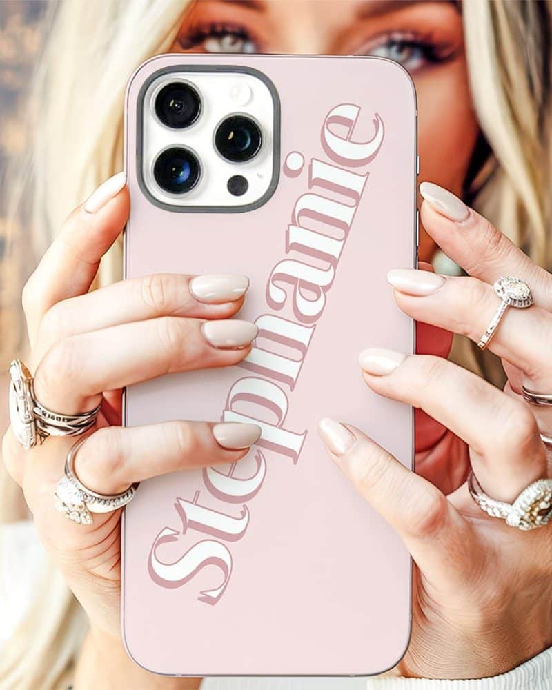 Woman holding a pink phone case with the name Stephanie printed on it.