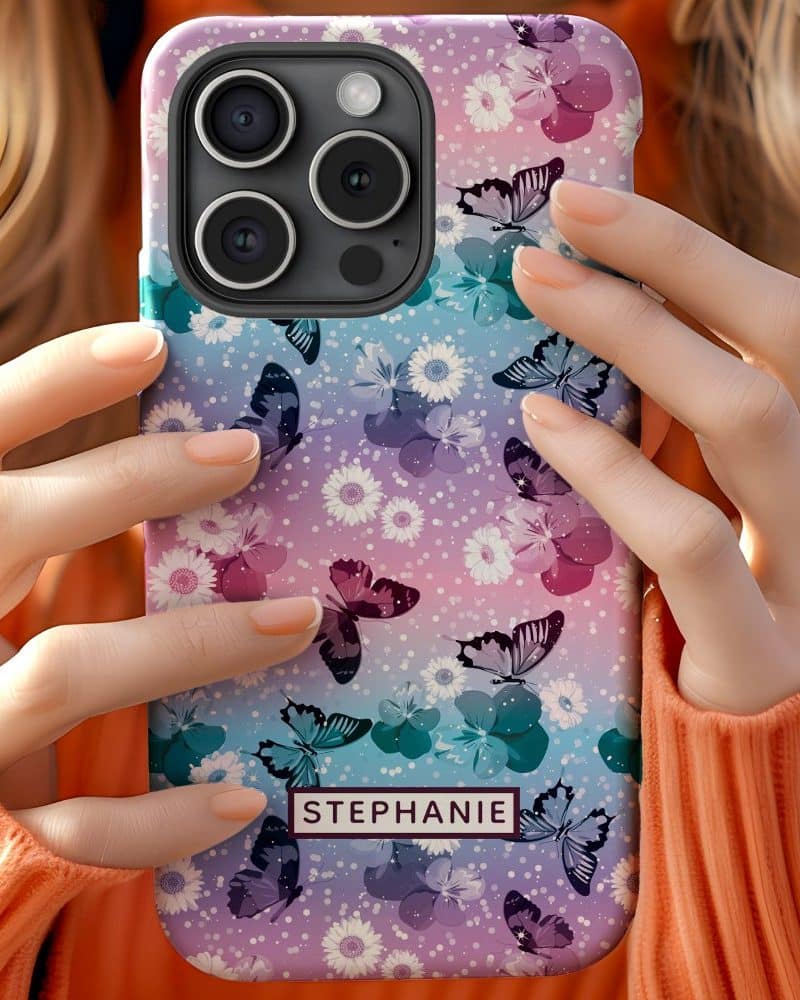 A person holds up a pastel phone case featuring a pattern of butterflies and flowers. The name Stephanie is visible on the case.