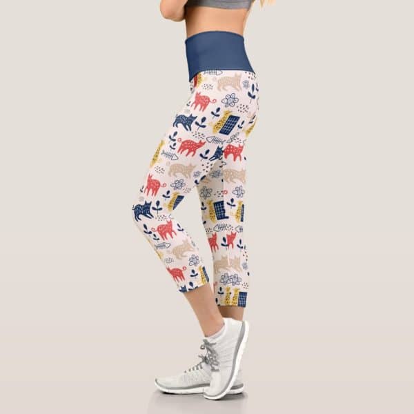 Cropped Leggings Featuring A Whimsical Cat Pattern In Red, Yellow, Blue, And Beige.