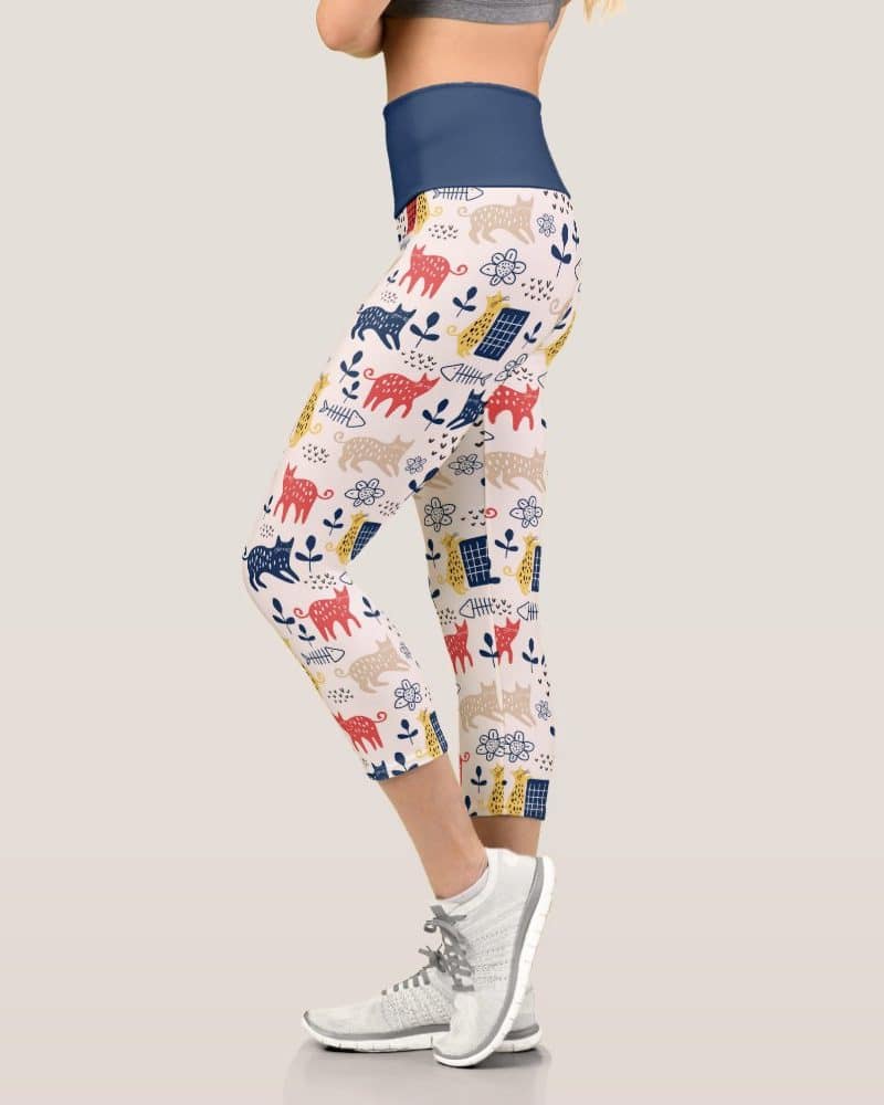Cropped leggings featuring a whimsical cat pattern in red, yellow, blue, and beige.
