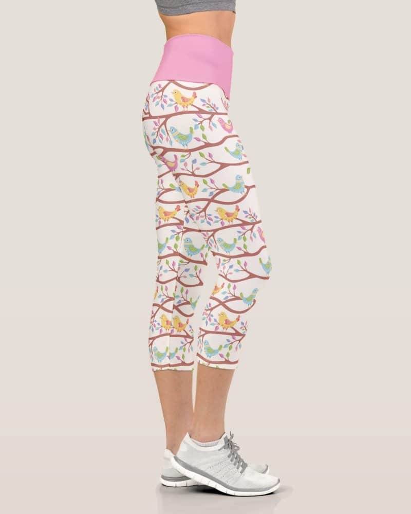 Women's cropped leggings with a pink waistband and a pattern of colorful birds on branches.