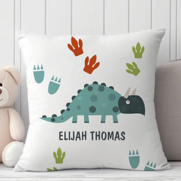 White Pillow With A Teal Dinosaur And Footprints, Personalized With The Name Elijah Thomas.