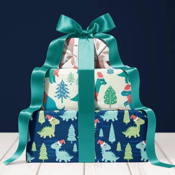 Three Christmas Presents Stacked, Wrapped In Dinosaur And Christmas Tree Patterned Paper, Tied With A Teal Ribbon.
