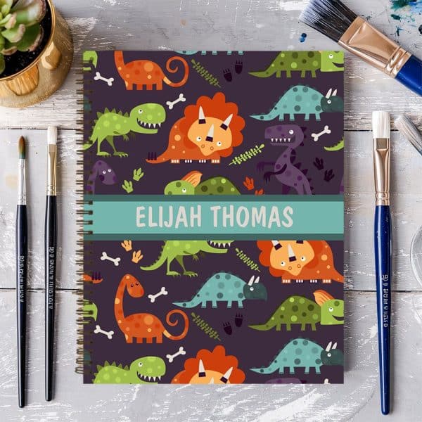 Spiral-Bound Notebook With A Dark Purple Cover Featuring A Colorful Dinosaur Pattern And The Name Elijah Thomas.