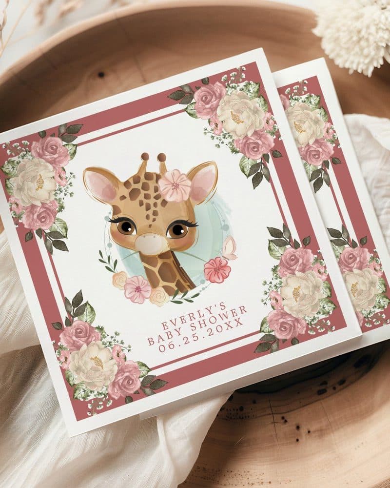 Baby shower invitation featuring a cute giraffe surrounded by blush pink flowers.