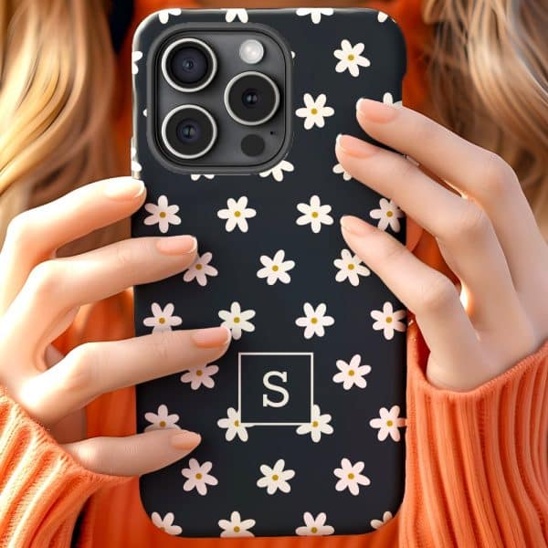 Close-Up Of Hands Holding A Dark Phone Case Decorated With White Daisies And A White Letter S.