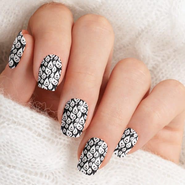 Close-Up Of A Hand With Fingernails Decorated With A Black And White Ghost Pattern.