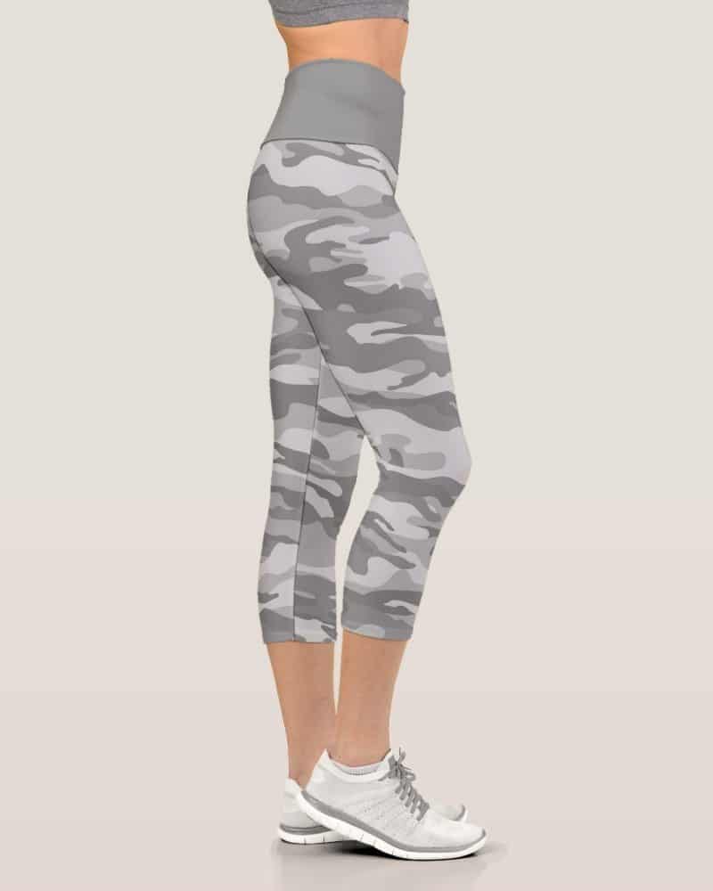 Side view of a woman's legs wearing gray camouflage cropped leggings and white athletic shoes.