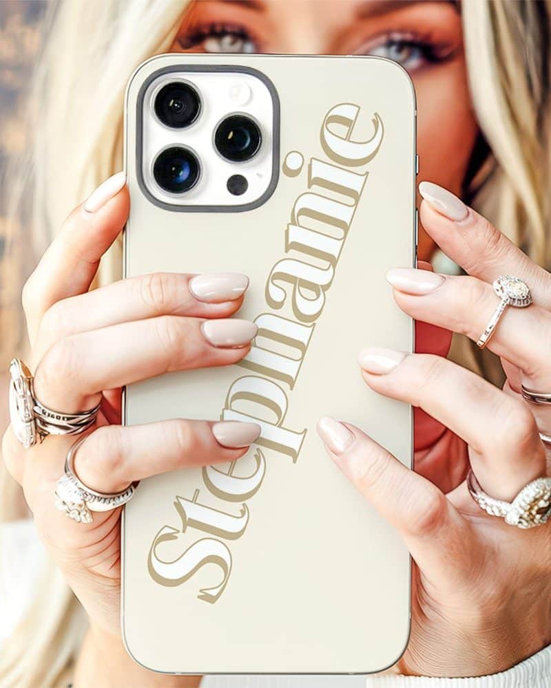 Close-up of a woman's hands holding a beige iPhone case with the name Stephanie printed on it.