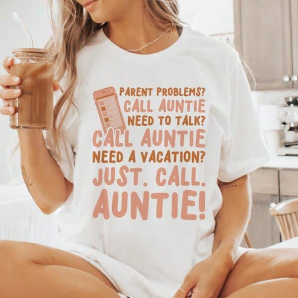 Woman Wearing A White T-Shirt With A Phone Graphic And Text That Says &Quot;Parent Problems? Call Auntie. Need To Talk? Call Auntie. Need A Vacation? Just Call Auntie!&Quot;