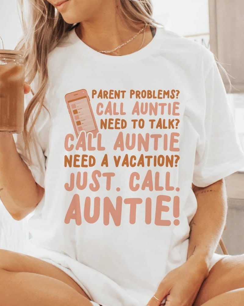 Woman wearing a white t-shirt with a phone graphic and text that says "Parent problems? Call Auntie. Need to talk? Call Auntie. Need a vacation? Just call Auntie!"