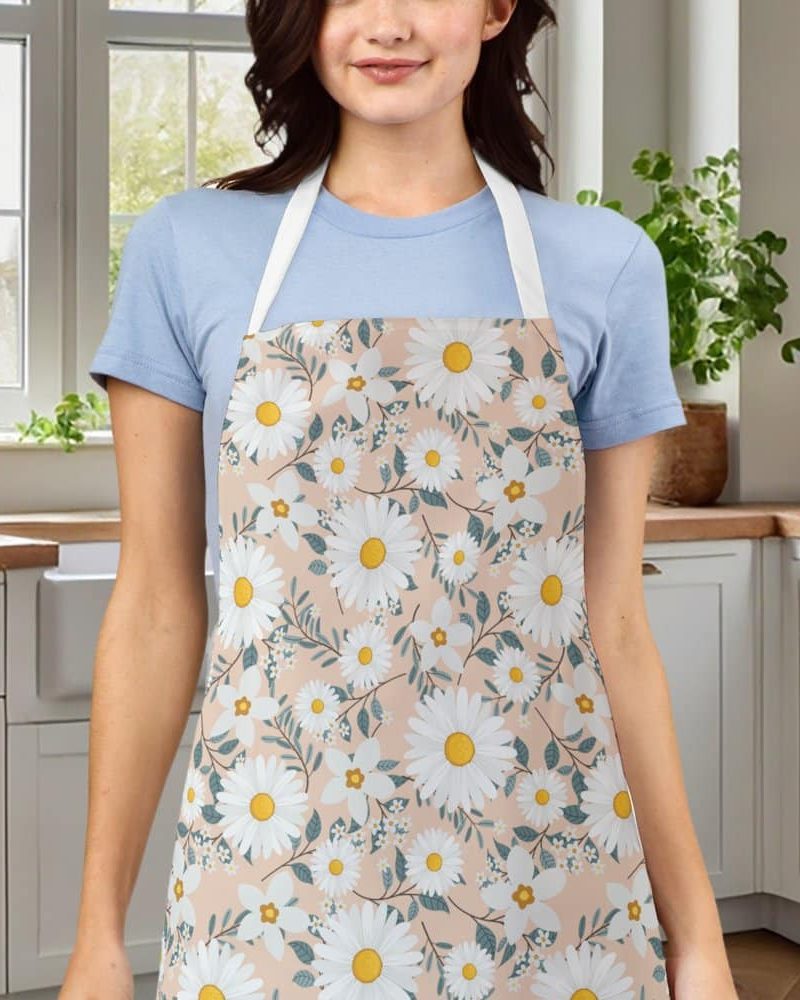 A woman wearing a peach-colored apron adorned with a daisy floral pattern.