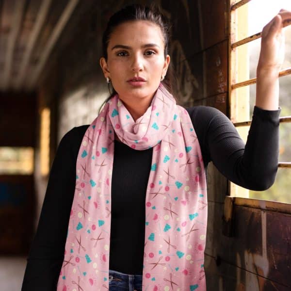 Woman Wearing A Pink Scarf With A Sewing Theme Pattern.