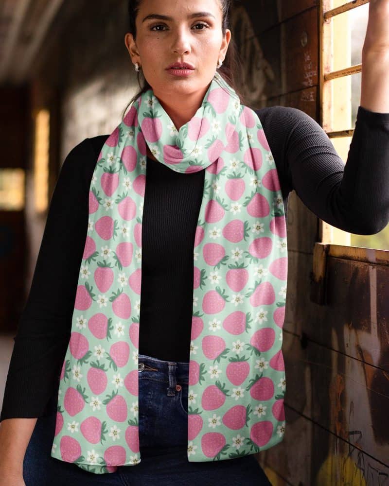 Woman wearing a light green strawberry print scarf.
