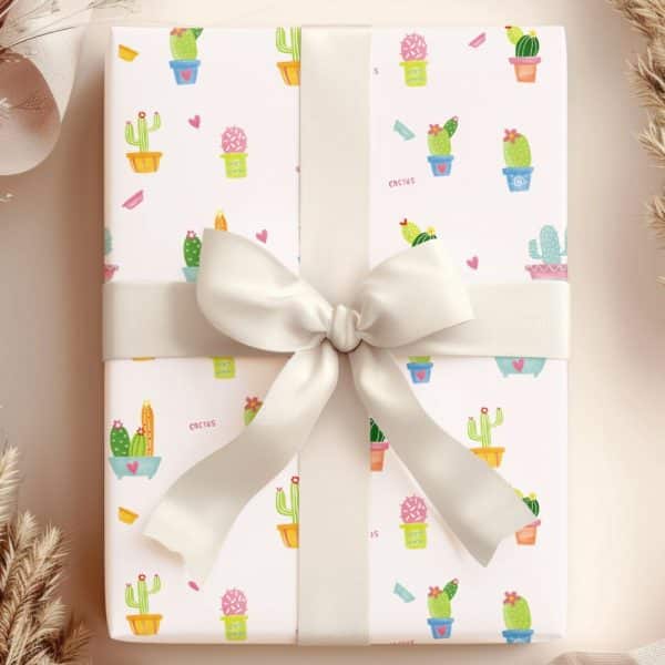 Gift Wrapped In White Paper With A Repeating Pattern Of Colorful Cacti In Pots. A Large Off-White Bow Adorns The Top.
