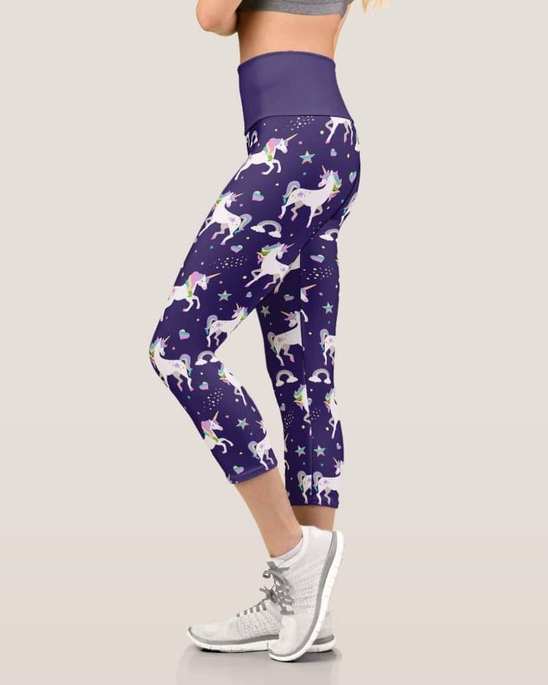 Purple capri leggings with a repeating pattern of white unicorns, rainbows, and stars.