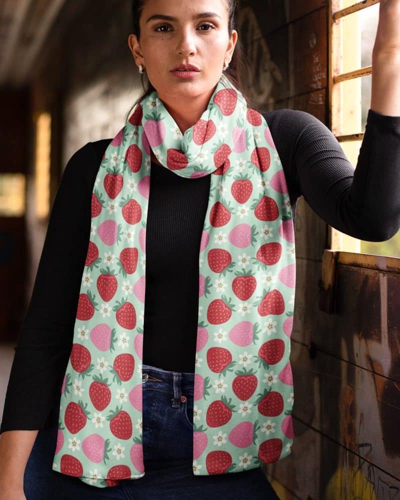 Woman wearing a mint green strawberry patterned scarf.