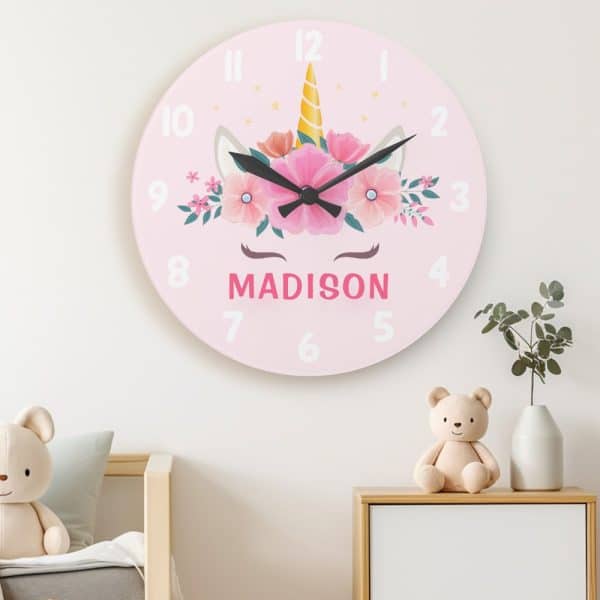 Pink Children'S Wall Clock Featuring A Unicorn Face With Flowers And The Name Madison.