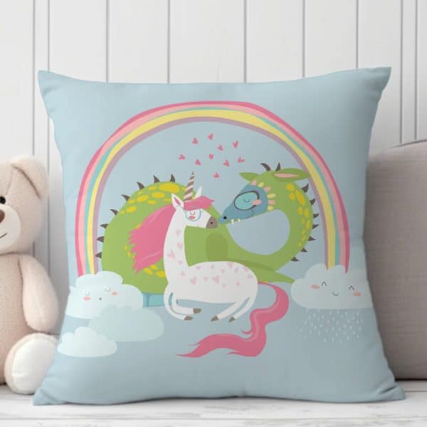 Light Blue Pillow With A Unicorn And Dragon Nuzzling Under A Rainbow.