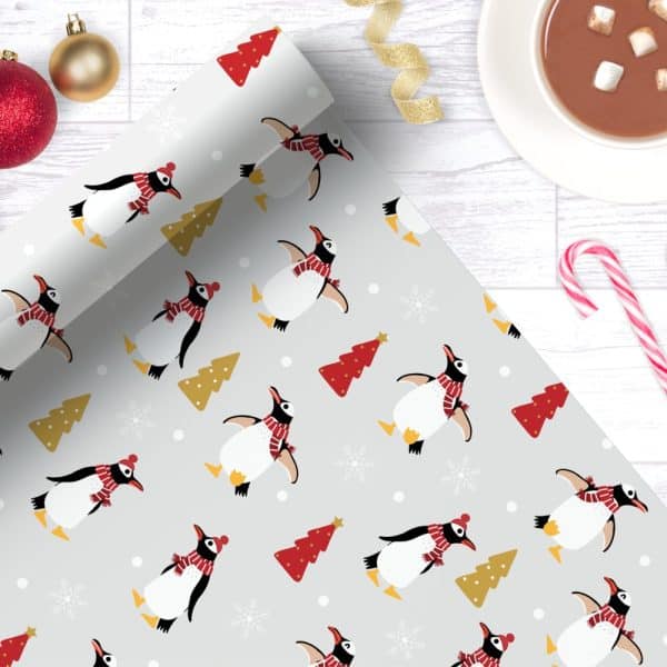 Grey Wrapping Paper With A Repeating Pattern Of Penguins Wearing Red Scarves And Hats, Alongside Small Christmas Trees.