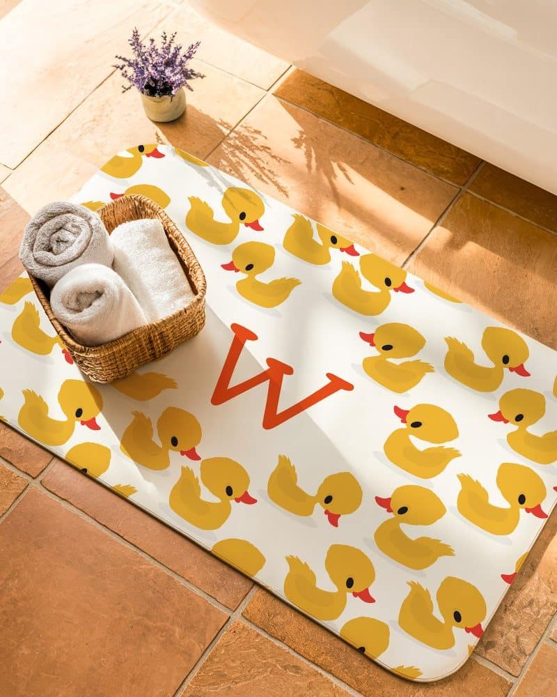 Bath mat with yellow rubber duckies and the letter W.