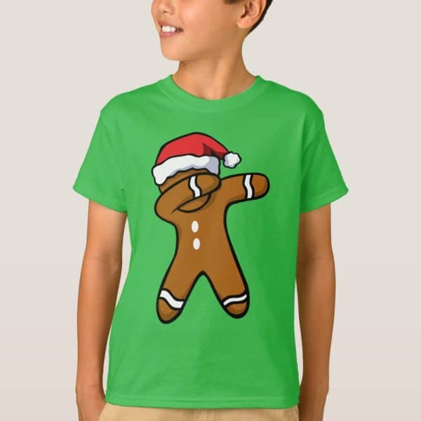 Child Wearing A Bright Green T-Shirt Featuring A Cartoon Gingerbread Man Wearing A Santa Hat And Dabbing.