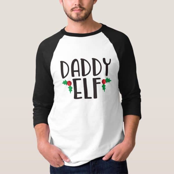 Man Wearing A White And Black Baseball Tee Shirt That Says Daddy Elf With Holly Berries.