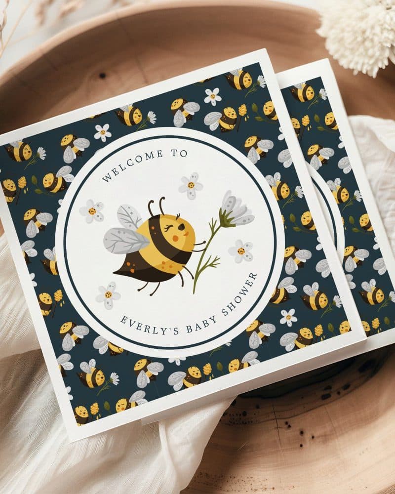 Baby shower invitation featuring a cute cartoon bee with a flower.
