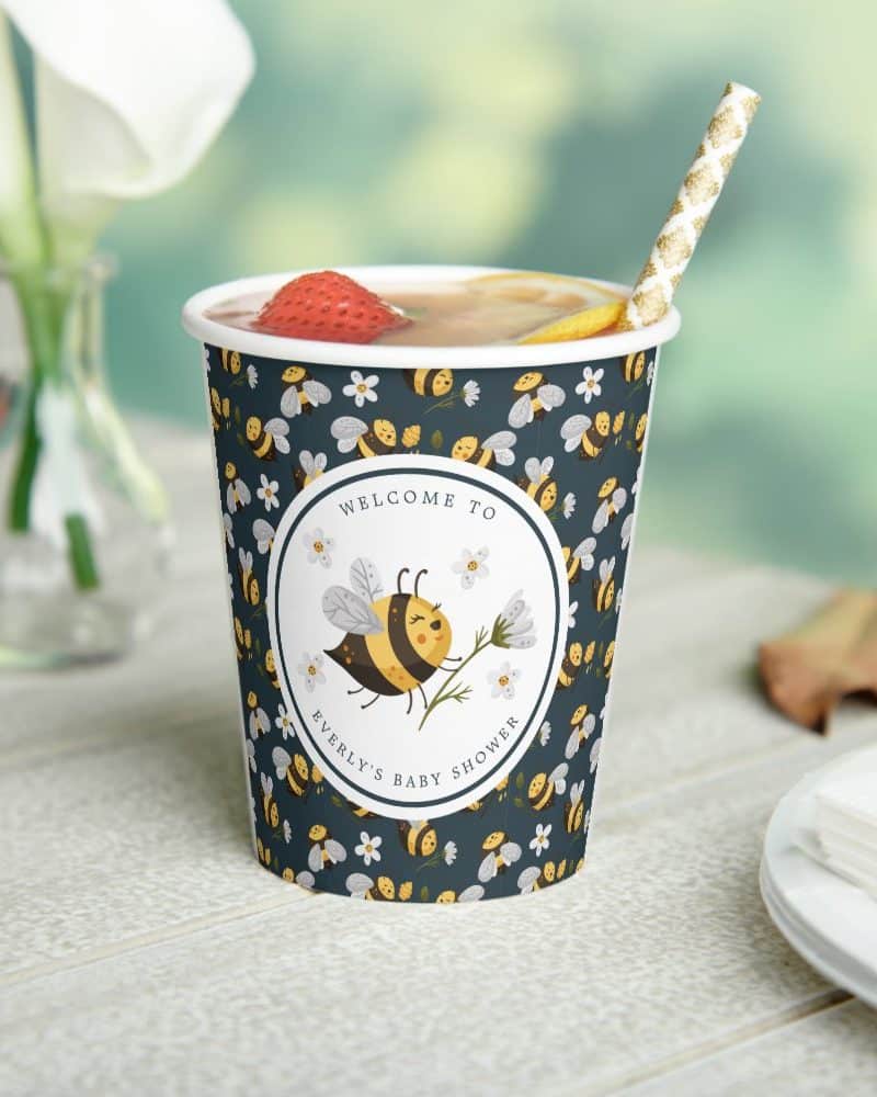 A dark-blue cup with a bee and flower design, announcing Everly's baby shower.