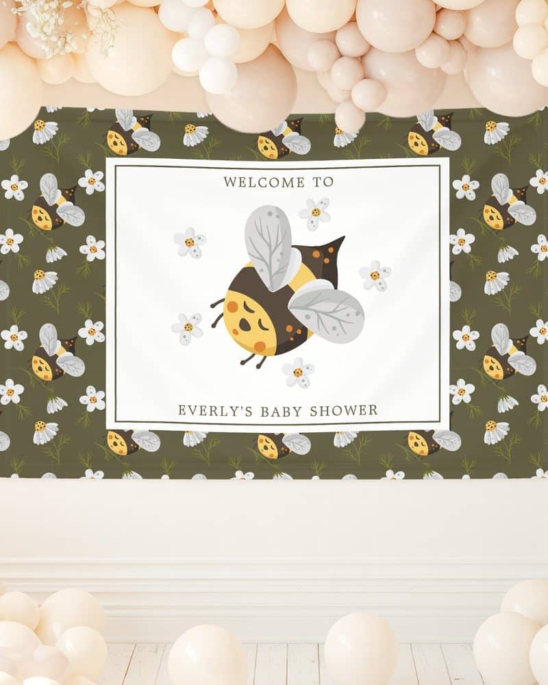 A baby shower banner featuring a cartoon bumble bee surrounded by small flowers. The banner says Welcome to Everly's Baby Shower.